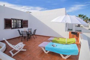 um pátio com uma mesa, cadeiras e um guarda-sol em Apartamento Los Fragosos em Puerto del Carmen