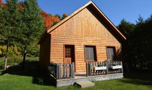 a small wooden cabin with a fence in the grass at La Sapinette in Val-David