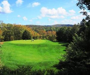 a large green field with people playing golf on it at La Sapinette in Val-David