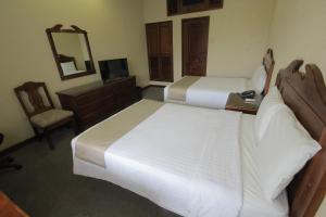 a bedroom with two beds and a desk and a mirror at Hotel San Antonio in Tampico