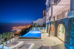 a villa with a swimming pool at night at Balancal Apartments and Villas Palheiro Village in Funchal