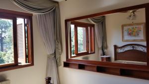 ein Schlafzimmer mit einem Spiegel, einem Bett und Fenstern in der Unterkunft Apartamento Monte Bianco in Gramado