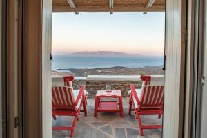 a patio with red chairs and a table and a view at Vathisthea in Kithnos