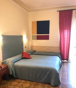een slaapkamer met een bed met een rood kussen erop bij Hotel Scala Greca in Siracusa