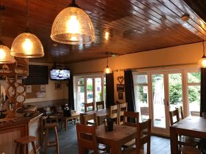 a restaurant with wooden ceilings and tables and chairs at Ty Mawr Hotel in Llanbedr