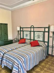 una camera da letto con un letto con due cuscini rossi sopra di Hotel Scala Greca a Siracusa