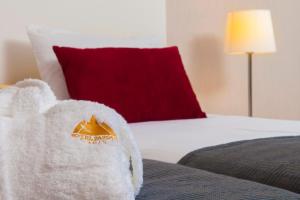 - une serviette blanche sur un lit avec un oreiller rouge dans l'établissement Hotel Parque Serra da Lousã, à Miranda do Corvo