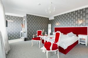 1 dormitorio con cama roja, mesa y sillas en Pensiunea Avy, en Haţeg