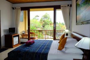 a bedroom with a bed with a view of a balcony at Jati 3 Bungalows and Spa in Ubud