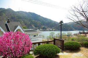 a house with a balcony with pink flowers on it at Ecran Pension in Gapyeong