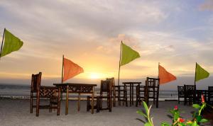 una mesa y sillas en la playa con banderas en The Coral Blue Oriental Beach Villas and Suites, en Bantayan Island