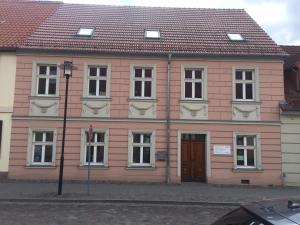 a pink building with white windows and a brown door at Studio Templin in Templin