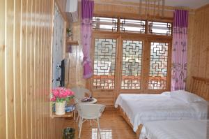 um quarto com 2 camas, uma mesa e uma janela em Yangjiajie Inn em Zhangjiajie