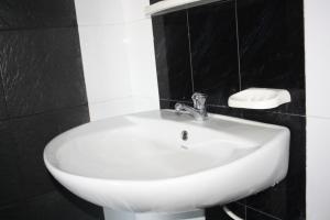 a white sink in a bathroom with black tiles at Moonlight Holiday Home Ella in Ella