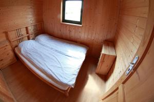 ウストロニエ・モルスキエにあるDomki letniskowe Czugoの木造キャビン内のベッド1台が備わる小さな客室です。