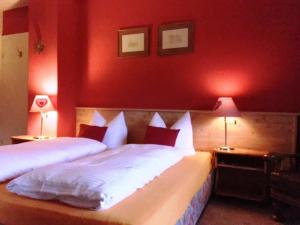1 Schlafzimmer mit 2 Betten mit roten Wänden und 2 Lampen in der Unterkunft Bäckeralm© - B&B 16 + in Mittenwald