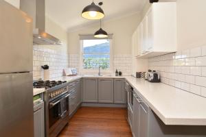 a kitchen with white cabinets and a sink and a window at Linda's Cottage @ the Hunter in Cessnock