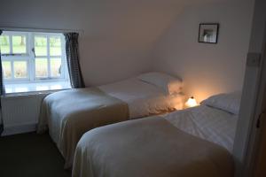 due letti in una piccola stanza con una finestra di Ceiros Cottage a Llangammarch Wells