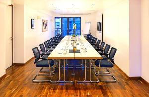 uma grande sala de conferências com uma mesa longa e cadeiras em Business Wieland Hotel em Dusseldorf