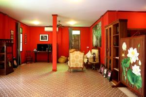 a living room with red walls and a chair at Le Jardin Hotel in Pakse