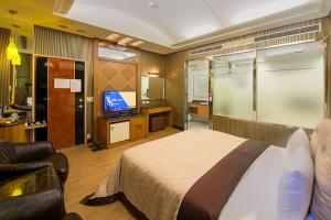 Lai Yin Motel في لونغتان: غرفة نوم بسرير وتلفزيون وأريكة