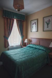 a bedroom with a green bed and a window at Her Majesty Hotel in London