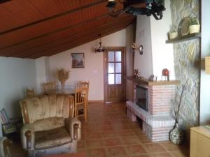 a living room with a fireplace and a chair at Casa Rural El Solarillo in Cazorla