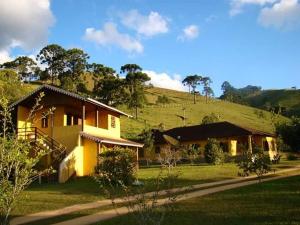 a yellow house with a hill in the background at Pousada Canário Da Terra in Visconde De Maua