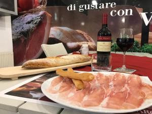 una mesa con un plato de carne y una botella de vino en Affittacamere Prosciutti Picaron, en Villanova