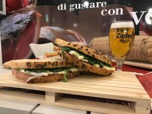 un sándwich en una tabla de cortar con un vaso de cerveza en Affittacamere Prosciutti Picaron, en Villanova