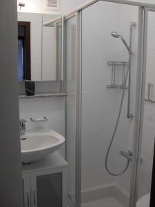 een witte badkamer met een douche en een wastafel bij Ferienwohnung Waldblick in Braunlage