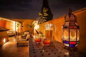una mesa con dos vasos de cerveza y una linterna en Riad Abjaou, en Marrakech