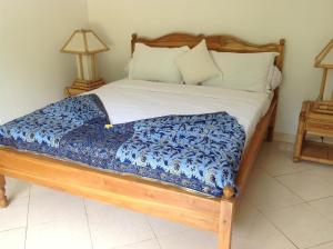 Una cama con un edredón azul y blanco. en Villa Nirwana en Lovina