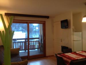 a living room with a sliding glass door to a balcony at Serre-Chevalier Chantemerle Eterlou in Saint-Chaffrey