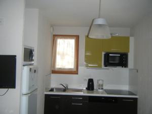 a kitchen with a sink and a refrigerator at Serre-Chevalier Chantemerle Eterlou in Saint-Chaffrey