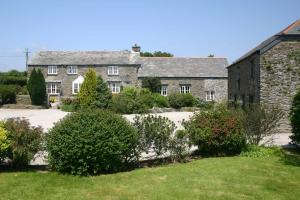 an old stone house with bushes in front of it at Talehay Cottages in Looe