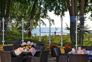 a restaurant with tables and chairs with the ocean in the background at Strandhotel Seerose in Kolpinsee