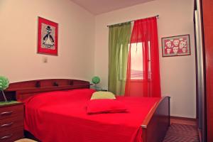 a bedroom with a red bed and a red window at Studio Silvana & Room Renata in Lumbarda