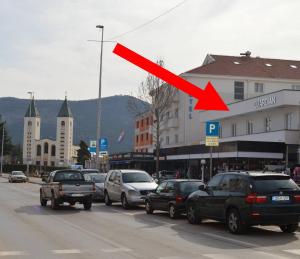 una flecha roja en una concurrida calle de la ciudad con coches en Rooms Guardian, en Međugorje