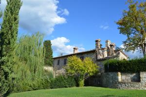 an old stone house with a stone wall and trees at Casa Vacanze Il Fornacino in Asciano