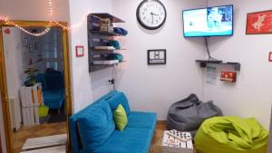 a living room with a blue couch and a clock at FlyFly Hostel , darmowy parking , rezerwuj przez urządzenia mobilne -10 procent in Wrocław