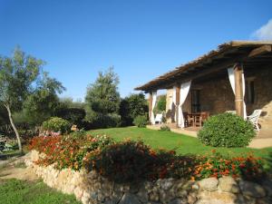 una casa con una pared de piedra y flores delante de ella en Le Tre Pietre, en Baja Sardinia