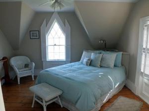 a bedroom with a bed and a chair and a window at Fisherman's Daughter B&B in Mahone Bay