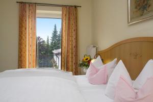 a bedroom with a bed with white pillows and a window at Haus BEER in Bad Tölz