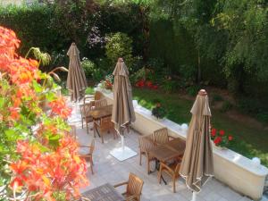 un patio avec des tables, des chaises et des parasols dans l'établissement Logis Hôtel-Restaurant Les Airelles, à Neufchâtel-en-Bray