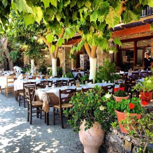 an outdoor restaurant with tables and chairs and plants at Platanos Rooms in Anopoli Sfakion