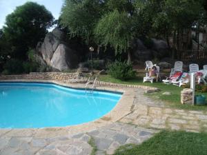 una piscina in un cortile con una persona seduta su una sedia di Residence Gardens a Porto Rotondo