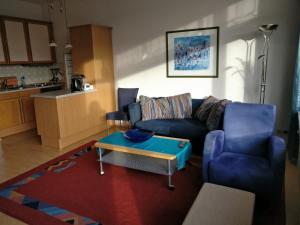 ein Wohnzimmer mit einem blauen Sofa und einem Tisch in der Unterkunft Appartement mit Südbalkon im Haus Feldbergblick in Kappel - Appartement 37 in Lenzkirch