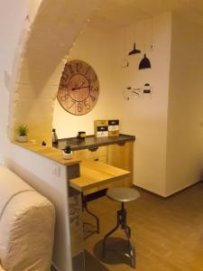 Zimmer mit einem Schreibtisch und einer Uhr an der Wand in der Unterkunft L'altro capo del filo in Syrakus