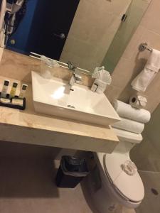 a bathroom with a sink and a toilet and a mirror at Hotel Roazi in Tizimín